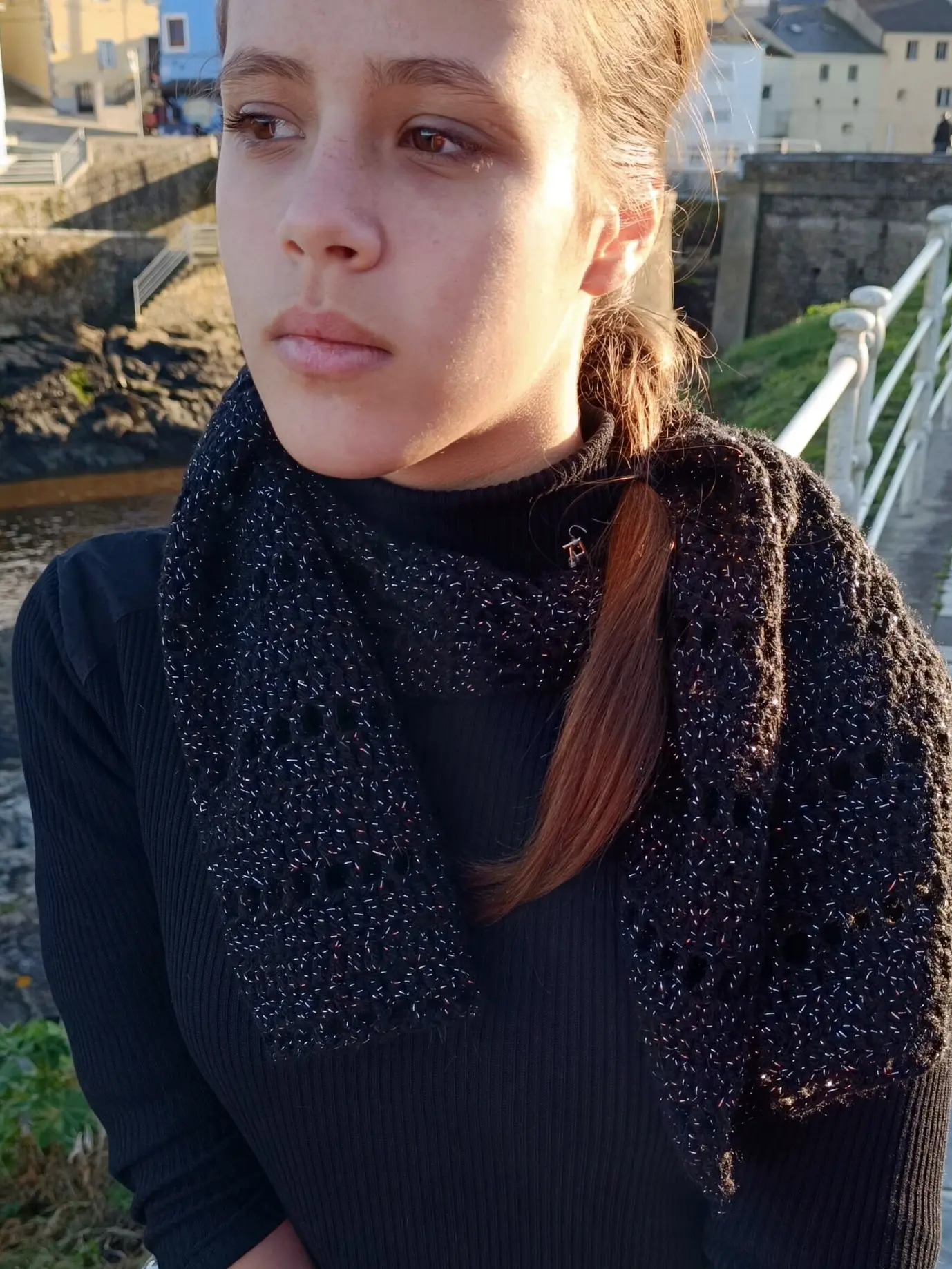 Bufanda simple de crochet negra colocada sobre un jersey negro